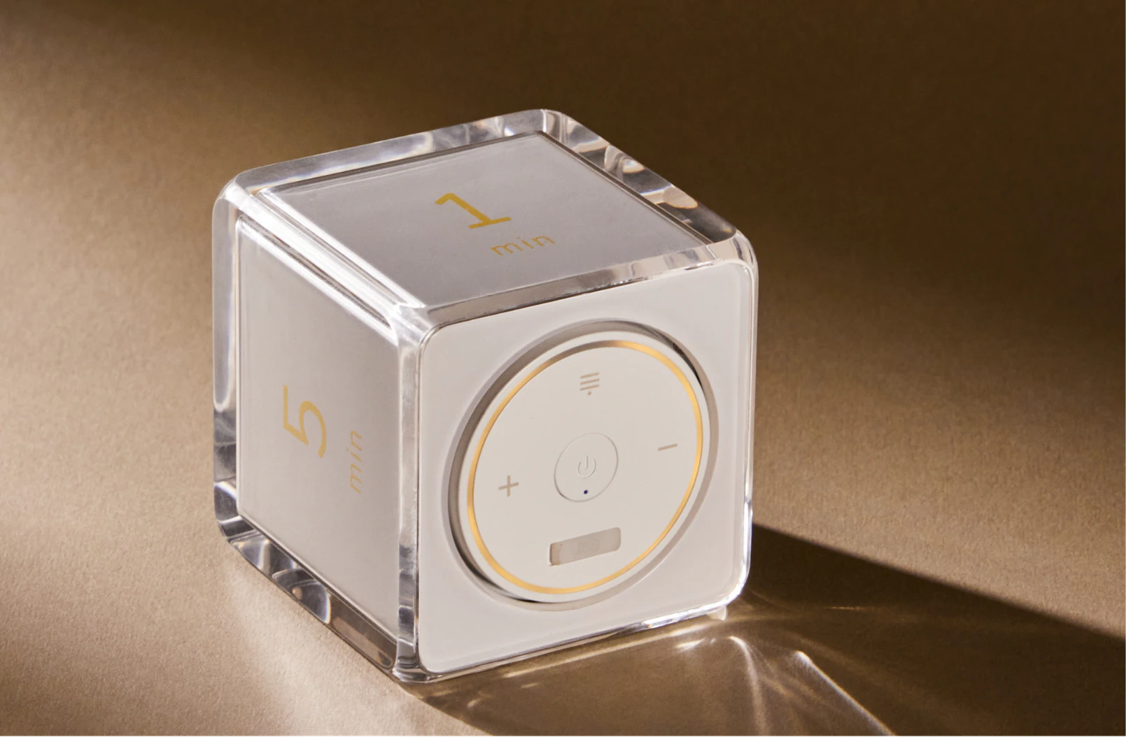 The clear Settledy cube showing its 1 and 5 minute faces and circular controls in warm sunlight
