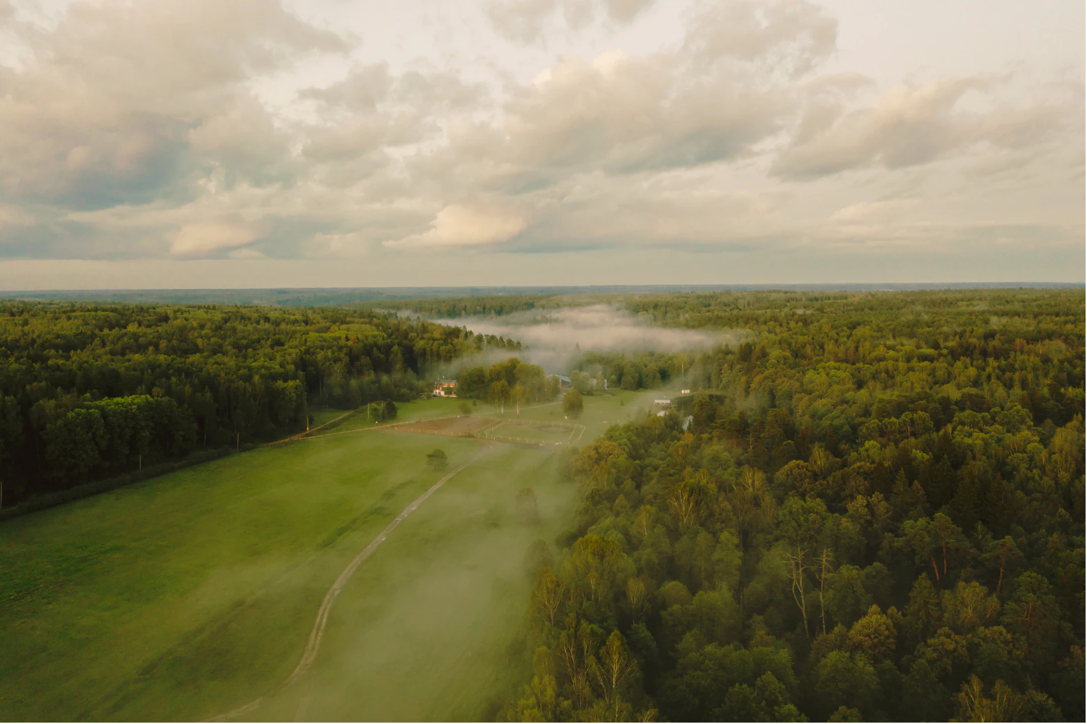 A misty green landscape beneath a wide cloud-filled sky